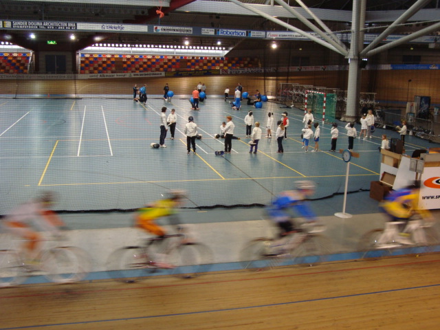 Zaalsporten op het middenterrein terwijl baanwielrenners langs fietsen